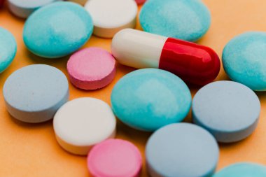Turuncu arka plandaki hapları kapat, ağrı kesici bağımlılığı kavramını. Bir sürü hap, aşırı doz. Antibiyotik tedavisi.