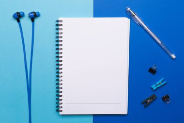Mavi arka planda kalem ve kulaklık olan boş bir defter..