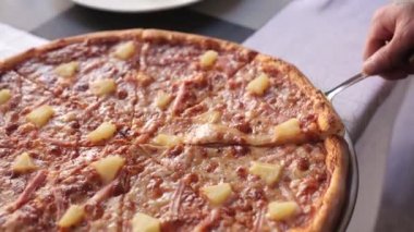 Restorandaki garson boş tabağa bir dilim Hawaii pizzası koyuyor. Lokantada yemek servisi yaptım..
