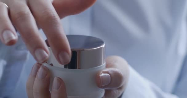 Sluiten van vrouwen handen openen container met gezichtscrème. — Stockvideo