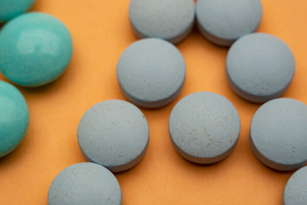 Close up of pills on orange background, concept of painkillers addiction. Lot of tablets, overdose. Antibiotics treatment.