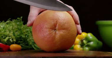 Meyveli vitamin salatası pişirmek için mutfak bıçağıyla greyfurt dilimlemek..