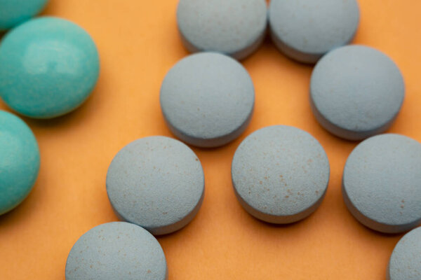 Close up of pills on orange background, concept of painkillers addiction. Lot of tablets, overdose.