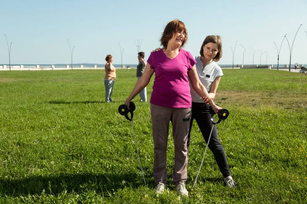 Une jeune formatrice aide une femme âgée à faire des exercices d'étirement. — Photo