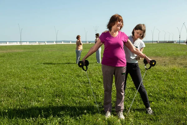 Une jeune formatrice aide une femme âgée à faire des exercices d'étirement. — Photo