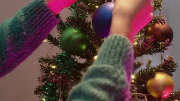 Mujer decoración de la mano del árbol de Navidad con bolas de colores. Año nuevo con luces de Navidad y abeto. — Vídeo de stock
