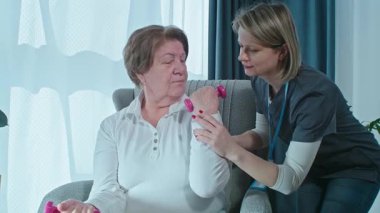 Bir kadın, bir fizyoterapist ve halter için halterci ya da yaşlı bir kadınla egzersiz yapan yaşlı bir bakıcı. Kadın ya da kişisel antrenör, sağlık ve sağlıkta yaşlı bir kadına yardım ediyor.. 