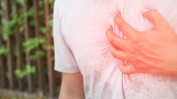 Man having chest pain - heart attack outdoors. or Heavy exercise causes the body to shocks heart disease. Focus color red on the chest area to show pain.