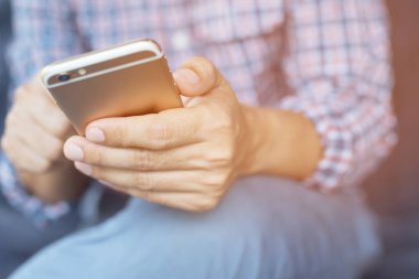 Genç iş adamı ofiste istirahat sırasında cep telefonu kullanarak gömlek ekose. mola sırasında cep telefonundan mesaj izlerken kanepe oturma.