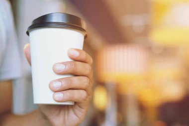 Genç adam el tutmak kağıt bardak almak uzağa kahve sıcak içecek kafe kahve dükkanı.