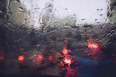 Akşam ları camın ön camına Yağmur Damlaları. şiddetli yağmurda sokak. Bokeh Kuyruk ışığı. yumuşak Odak. Lütfen dikkatli sür, kaygan yoldan. yumuşak odak.