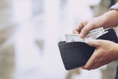 Bir adamın elinde cüzdan tutan işadamı cebinden para alıyor.