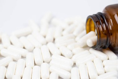 Derialtı şırıngası ve ilaç şişesi dökülüyor. Su toplayan kapsüllerdeki renkli haplar beyaz arka plandaki tabletlere yükleniyor. İlaç tıbbi sağlık cerrahisi konsepti. en üstteki görünüm.