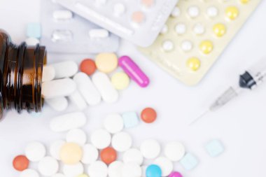 Derialtı şırıngası ve ilaç şişesi dökülüyor. Su toplayan kapsüllerdeki renkli haplar beyaz arka plandaki tabletlere yükleniyor. İlaç tıbbi sağlık cerrahisi konsepti. en üstteki görünüm.