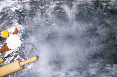 Genç eller, koyu siyah masanın üzerinde taze un ve hamurlu merdaneli fırın arka planında merdaneyle püre tutarlar. Metin için boş alan. Üst görünüm