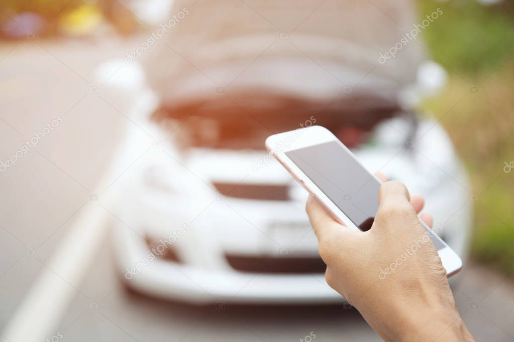 close up woman hand using a mobile smart phone call a car mechanic ask for help assistance because car broken roadside. people journey standing wait beside road broken car background.