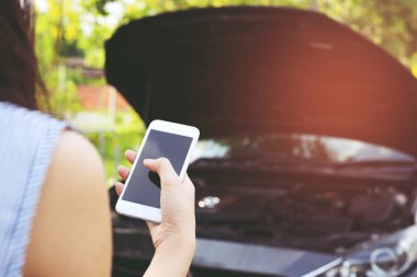 bir mobil akıllı telefon arama kullanarak kadın el yakın yukarı bir araba tamirci yardım isteyin çünkü araba yol kenarında kırık. boş ekran boş.