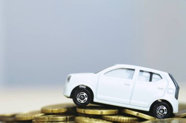Bir sürü para yığılmış bozuk paraların üzerinde küçük oyuncak beyaz araba. banka kredileri için maliyetleri finans. sigorta, araba finans konsepti satın alma. satın almak ve taksitle ödeme aşağı ödeme bir araba.