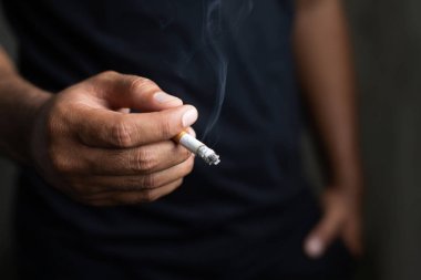 elinde sigara içen adam. Sigara dumanı yayıldı. koyu arka plan