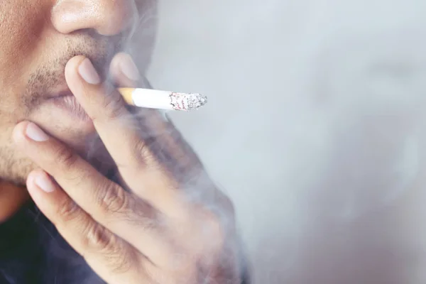 タバコを手にタバコを持っている男 タバコの煙が広がった暗い背景 — ストック写真
