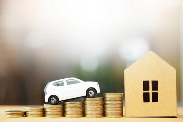 Business man and close up hand holding model of toy car and home on over a lot money of stacked coins - insurance, loan and buying car and home finance concept. buy and installments down payment a car.and home