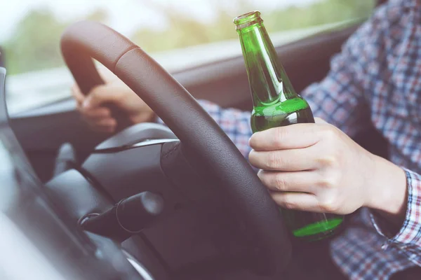 yakın el Sarhoş genç adam bir şişe bira ile bir araba sürerken. İçki içme ve araba kullanma. Tehlike sarhoşken araba kullanmak ölüm olabilir..