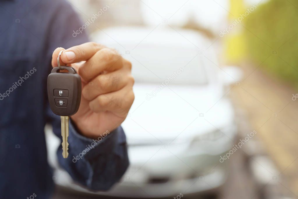 Car key, businessman handing over gives the car key to the other man on car background.