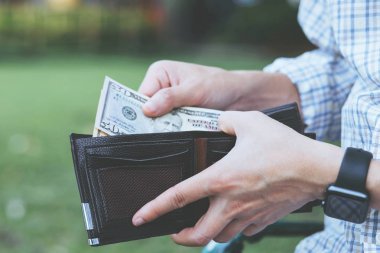 Bir adamın elinde cüzdan tutan işadamı cebinden para alıyor.