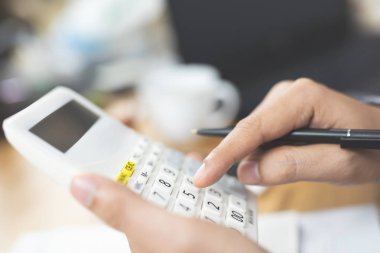 Hesap makinesi kullanarak işadamı elini kapatın ve not defterine yazarak not lar hesaplatArak ev ofisinde finans yapıyor. Tasarruf finans kavramı. not defteri