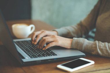 İş kadını serbest bilgisayar dizüstü bilgisayar ve cep akıllı telefon üzerinde çalışan kullanarak bir kafe kahve dükkanında masaahşap kahve fincanı ile iş göndermek. çalışan kadınlar.