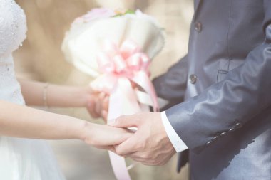 Sevgi dolu Genç erkek ve kadın aşk evli çift el ele tutuşarak ve tören düğün günü evlenmek sahne birlikte durmak. çift sevgilisi el sıkışma el sallamak gül çiçek buketi ile evlenmek teklif.