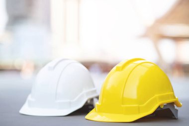 sarı ve beyaz sert emniyet aşınma kask şapka projede inşaat yerinde bina üzerinde beton zemin üzerinde güneş ışığı ile şehir. mühendis veya işçi olarak iş adamı için kask. kavramı güvenlik ilk.