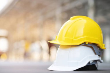 sarı ve beyaz sert emniyet aşınma kask şapka projede inşaat yerinde bina üzerinde beton zemin üzerinde güneş ışığı ile şehir. mühendis veya işçi olarak iş adamı için kask. kavramı güvenlik ilk.