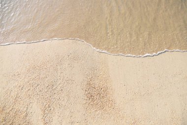Kumlu plajda yumuşak dalga akışı güzel okyanus kapatın. Arka plan. akşam güneş ışığı. üst görünüm.