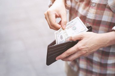 Bir adamın elinde cüzdan tutan işadamı cebinden para alıyor.