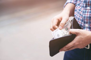 Bir adamın elinde cüzdan tutan işadamı cebinden para alıyor.