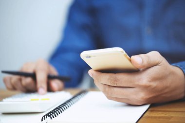 onu ve cep akıllı telefon üzerinde hesap makinesi kullanarak iş adamı nın el görünümü yakın matematiksel hesaplamalar için kullanılan düğme klavye. belgeler masaya yatırılır. kavram hesap finansmanı hesaplamak