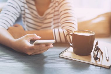 kahve içerken kafede ahşap masada içmeye hazır sıcak siyah bir fincan tutan kadın elleri.