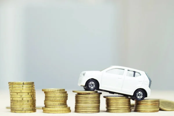 Little toy white car over a lot of money stacked coins. for bank loans costs finance. insurance, buying car finance concept. buy and pay by installments down payment a car.