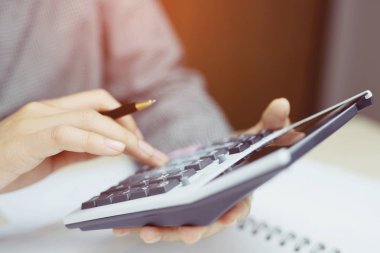 Yakın genç kadın el bir not defterine yazıyor ve hesap makinesi kullanarak home ofis finans yapıyor notlar muhasebe yapma sayma. Tasarruf finans kavramı. not defteri