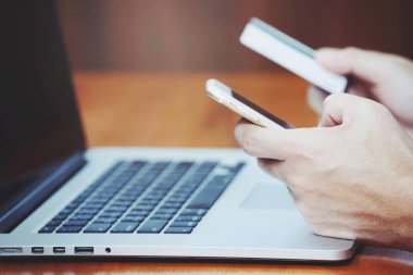 kredi kartı tutan ve telefon ve bilgisayar dizüstü bilgisayar kullanarak insanların ellerini kapatın. Online alışveriş satın alma Satış veya Ödeme.