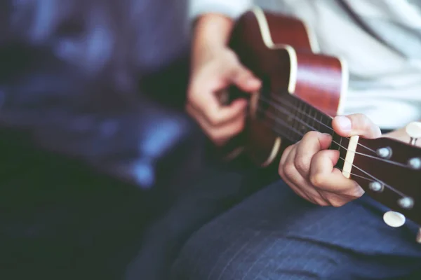 Zbliżenie Młodego Mężczyzny Ręce Grając Gitarze Akustycznej Ukulele Kanapie Siedzieć — Zdjęcie stockowe
