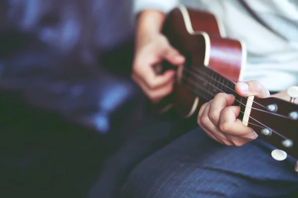 Closeup Fiatalember Kezében Akusztikus Gitár Ukulele Kanapén Ülni Élvezze Nappaliban — Stock Fotó