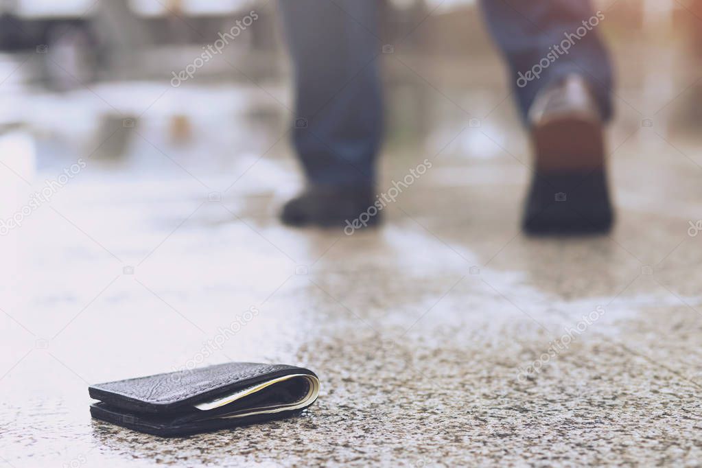 businessman had lost leather wallet with money on the street. Close-up of wallet lying on the sidewalk in during the trip to work.