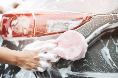 insanlar adam araba yıkama kıdamak için el pembe sünger tutarak. Konsept oto yıkama temiz.