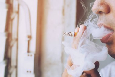 Elinde sigara içen adam. Sigara dumanı yayılması.