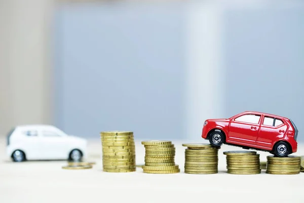 Little white and red two car over a lot of money stacked coins. for bank loans costs finance. insurance, buying car finance concept. buy and pay by installments down payment a car.