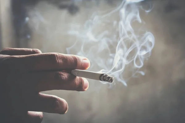 その男は手にタバコを吸っている タバコの煙が広がる — ストック写真