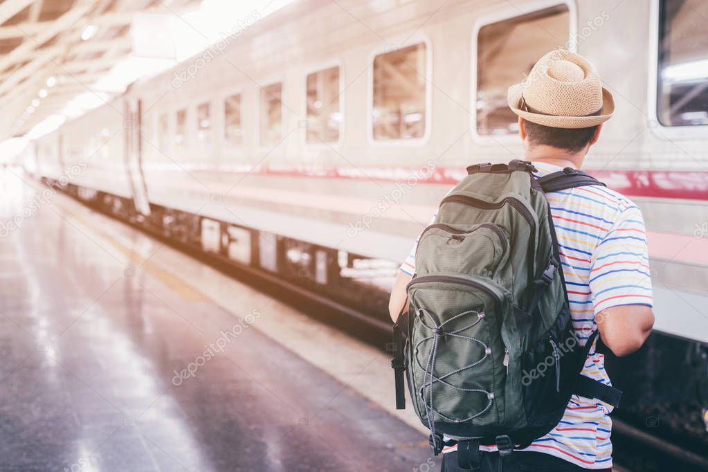 The passengers are stand waiting for the Station platform. Young man traveler with backpack looking waiting for train. the tourist travel Get ready for departure concept.