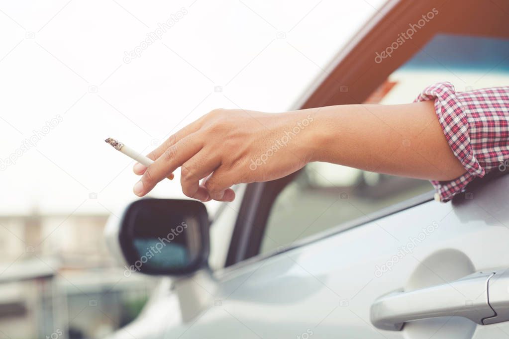 close up hand smoking a cigarette in car.